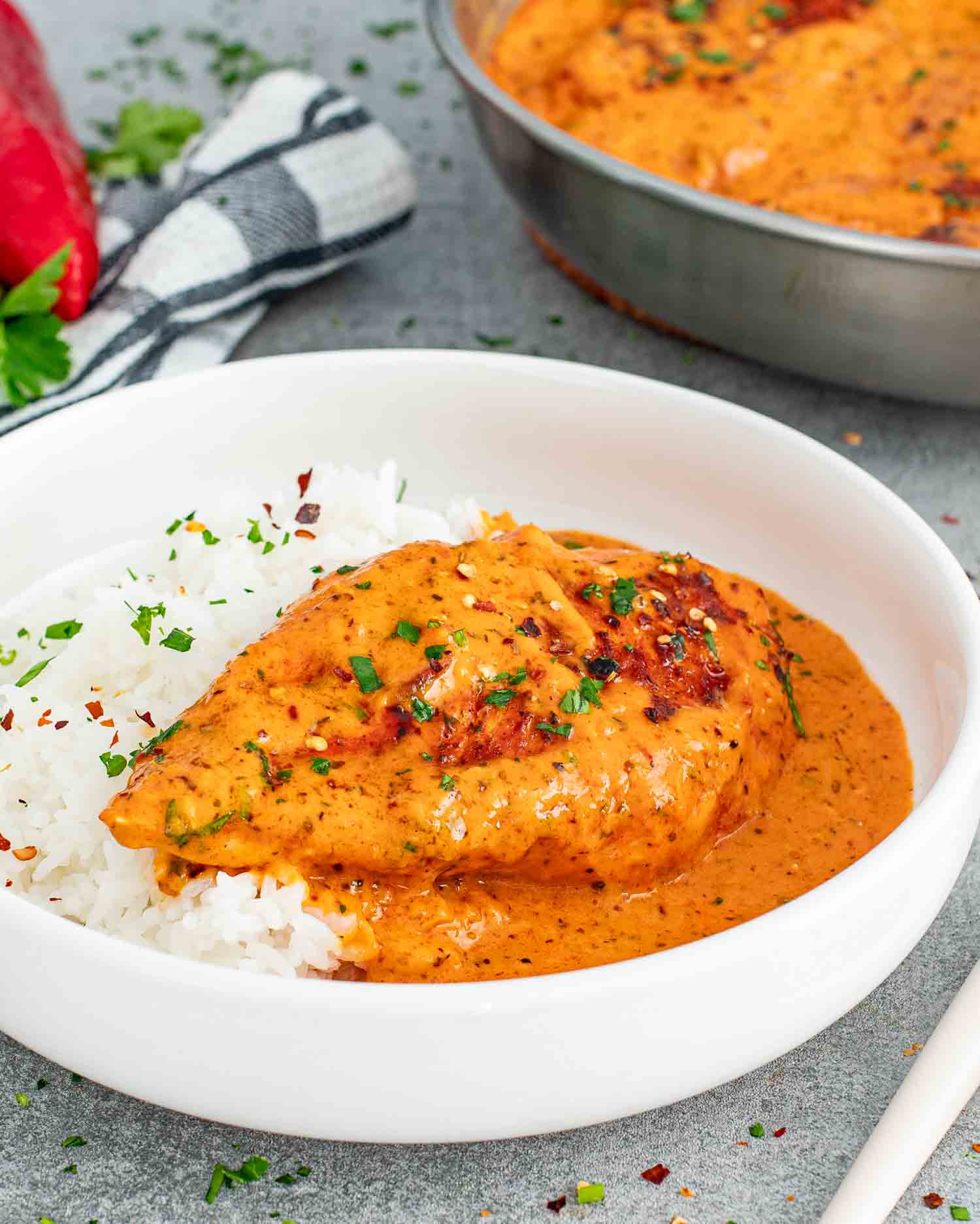a roasted red pepper chicken breast with rice in a white plate.
