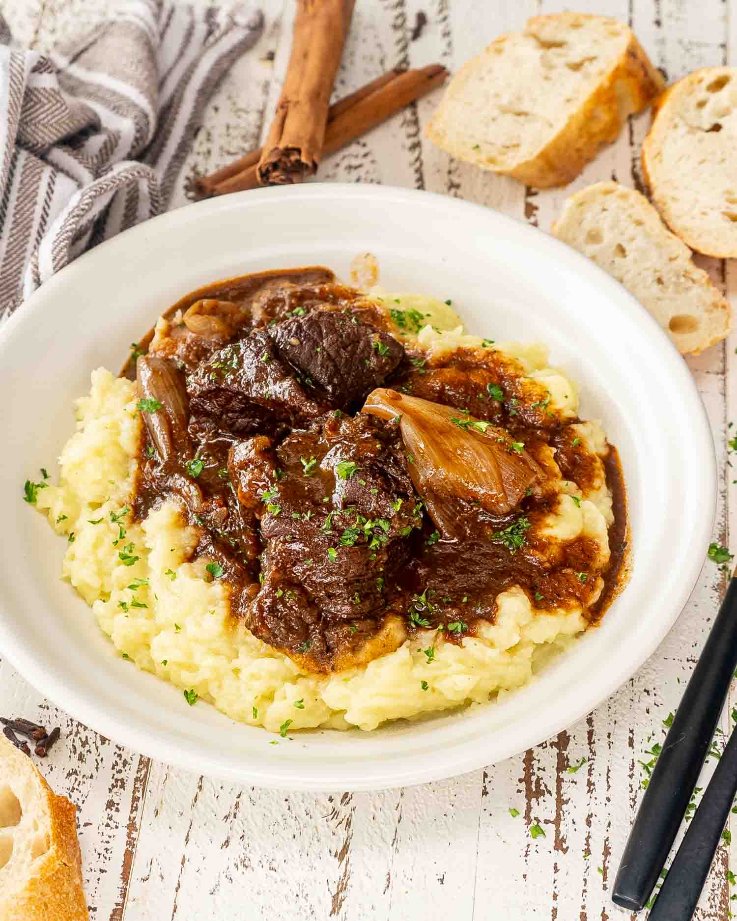 a serving of beef stifado over a bed of mashed potatoes.