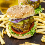a delicious cheeseburger with secret sauce on a cutting board surrounded by french fries.