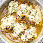 Golden chicken breasts topped with melted cheese, prosciutto, and sautéed mushrooms, served in a flavorful sauce and garnished with herbs.