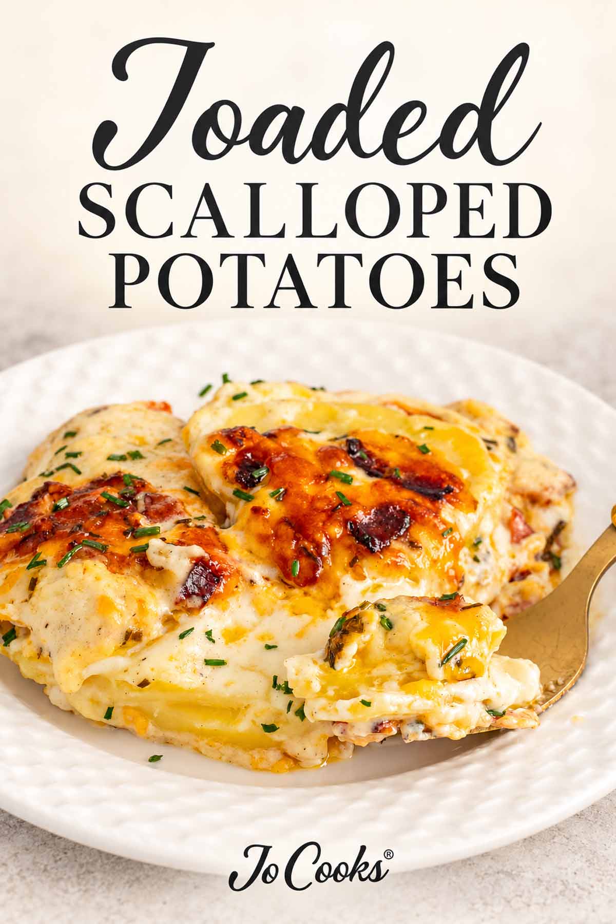 Creamy loaded scalloped potatoes on a white plate with a gold fork, topped with recipe title and Jo Cooks® logo.