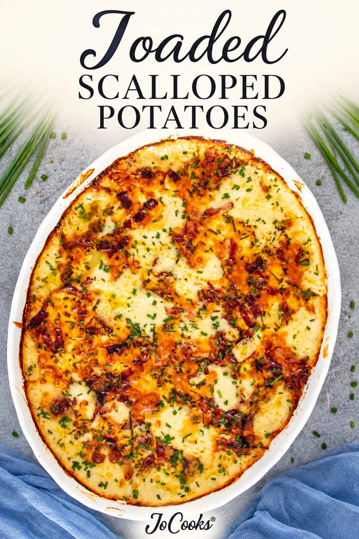 Overhead view of loaded scalloped potatoes topped with browned cheese, bacon, and chives, with recipe title and Jo Cooks® logo.