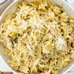 Bowl of slow cooker garlic Parmesan chicken pasta, topped with shredded Parmesan and parsley, ready to serve for dinner.