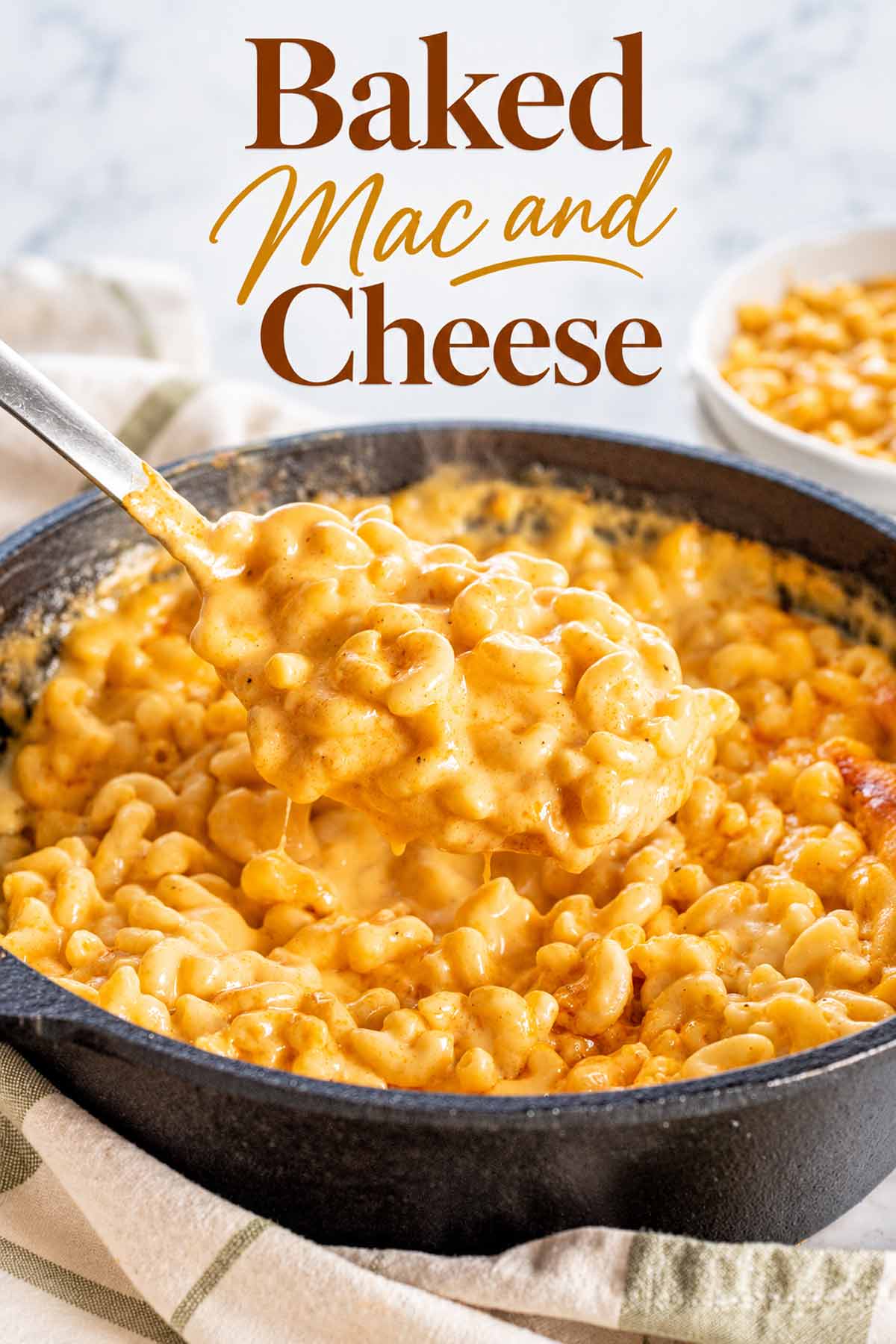 Spoonful of creamy baked mac and cheese lifted from a skillet, with golden melted cheese and crisp edges.