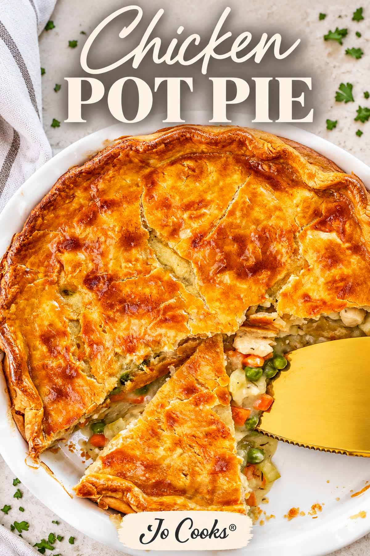 Whole golden chicken pot pie with one slice removed, revealing creamy chicken, peas, carrots, and potatoes inside.