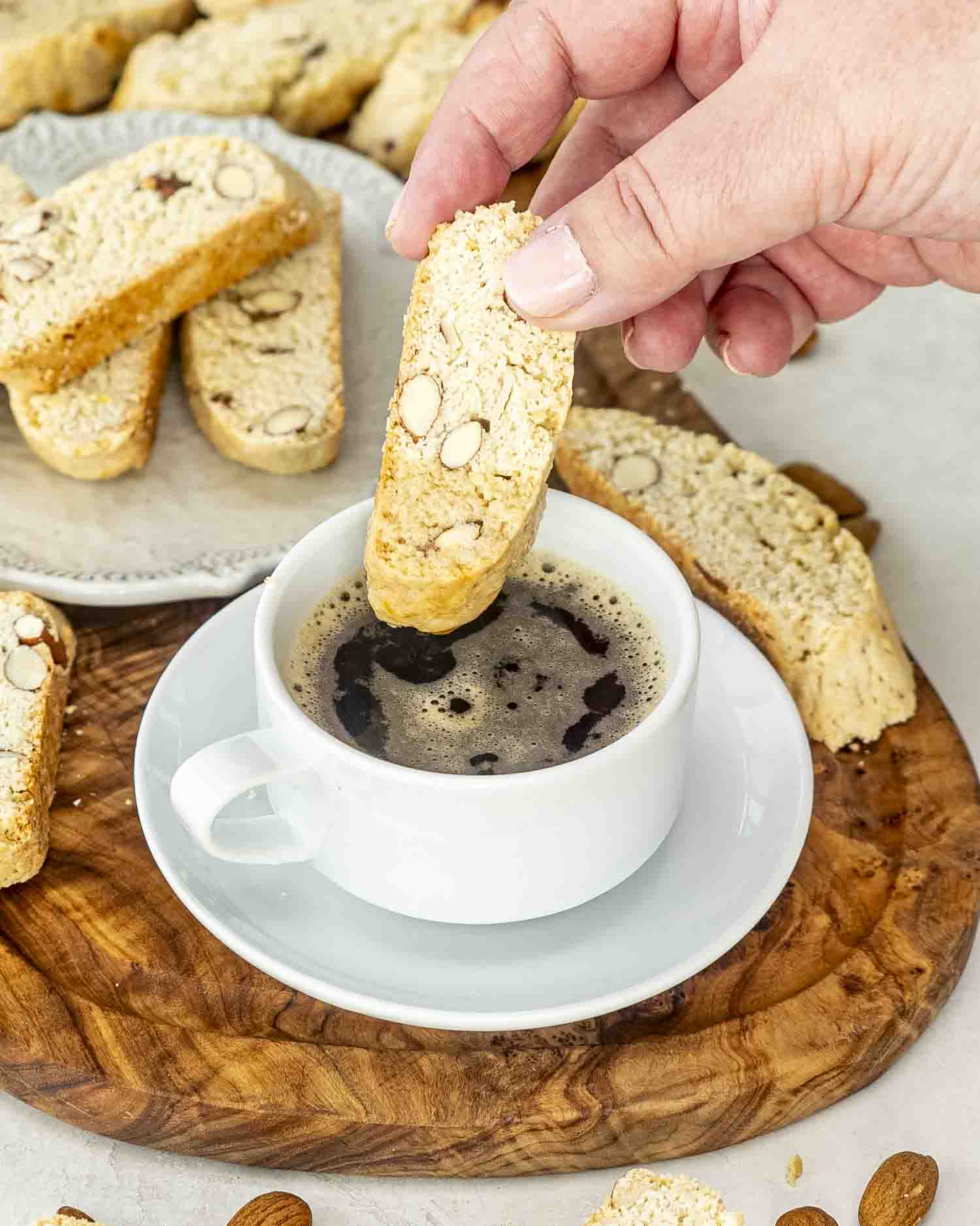 almond biscotti with a cup of coffee on a cutting board.