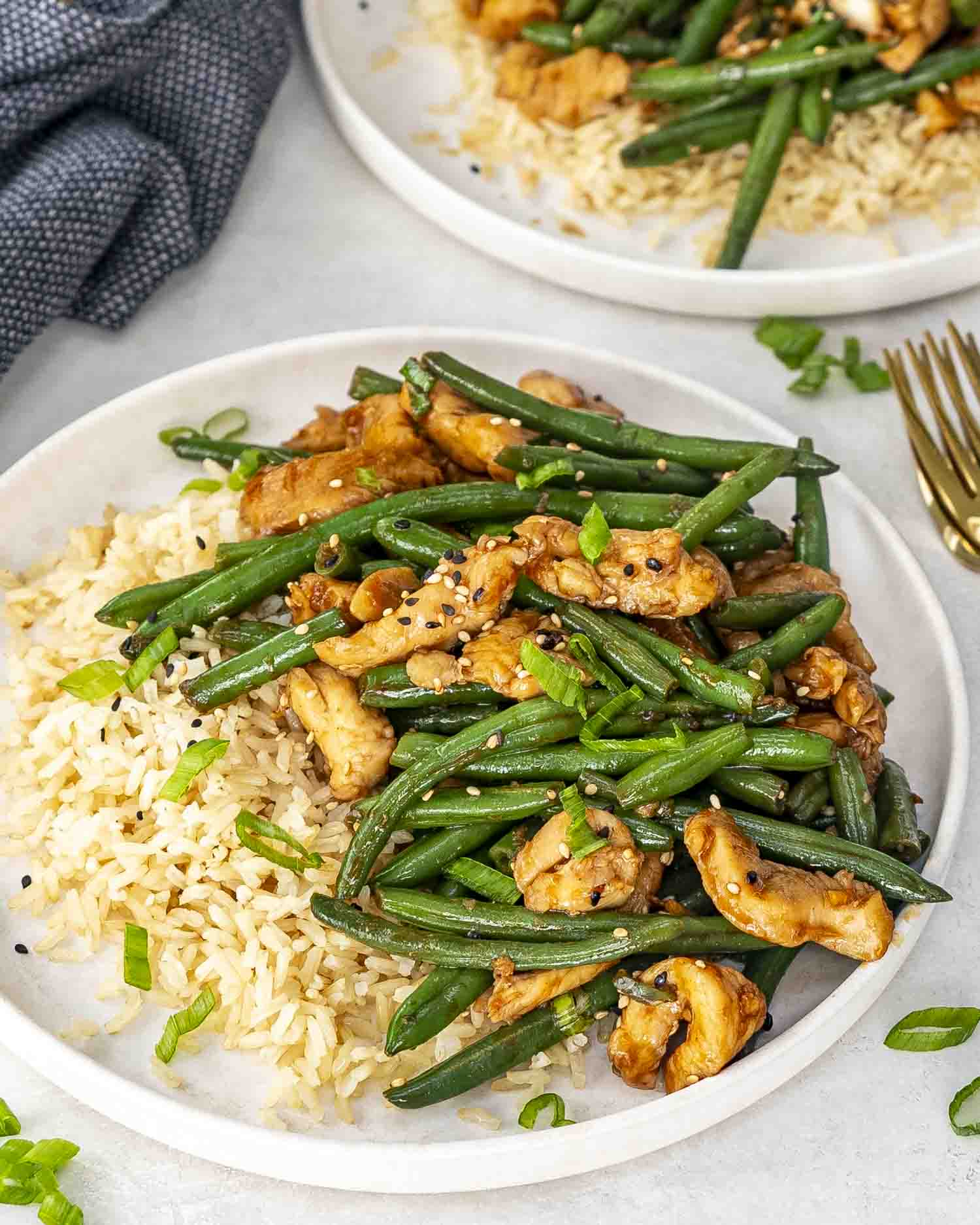 a serving of chicken green bean stir fry in a white plate with a serving of rice.