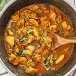 Panang Chicken Curry in a wok, featuring tender chicken pieces coated in a rich, aromatic curry sauce garnished with fresh basil and red chilies, ready to serve.