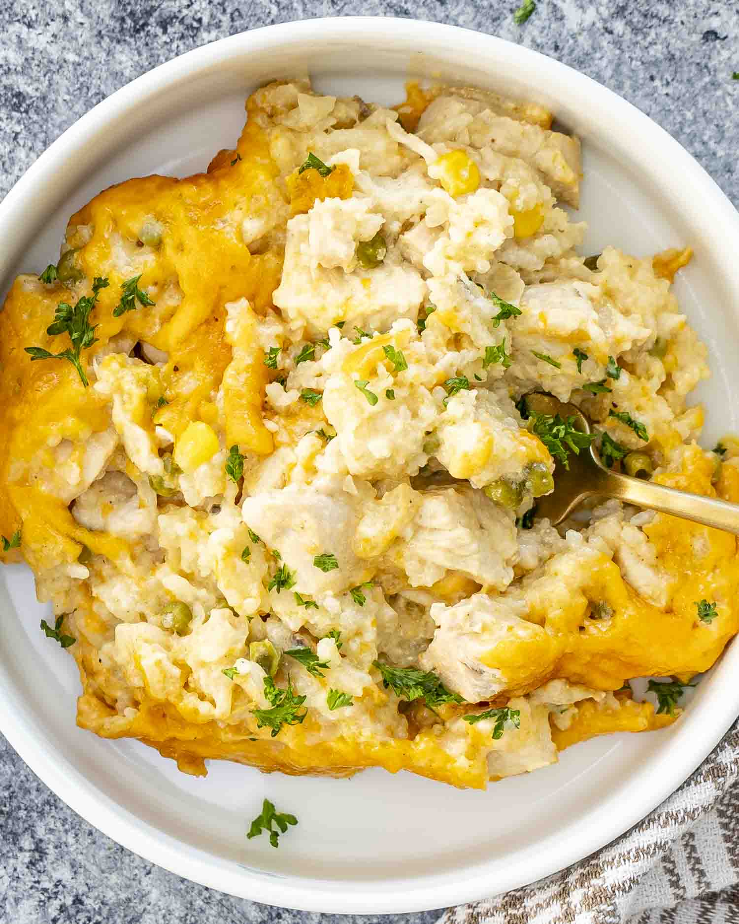 a serving of chicken and rice casserole in a white bowl with a golden fork inside.