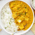 Bowl of matar paneer served alongside white basmati rice, perfect for scooping with naan or roti.