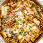 Overhead shot of bubbling beef and pepper pasta skillet fresh from broiler, melted mozzarella golden and sprinkled with parsley.