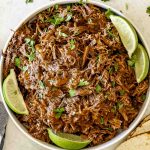 Juicy slow cooked pulled beef topped with rich BBQ sauce and fresh parsley, served with lime wedges.