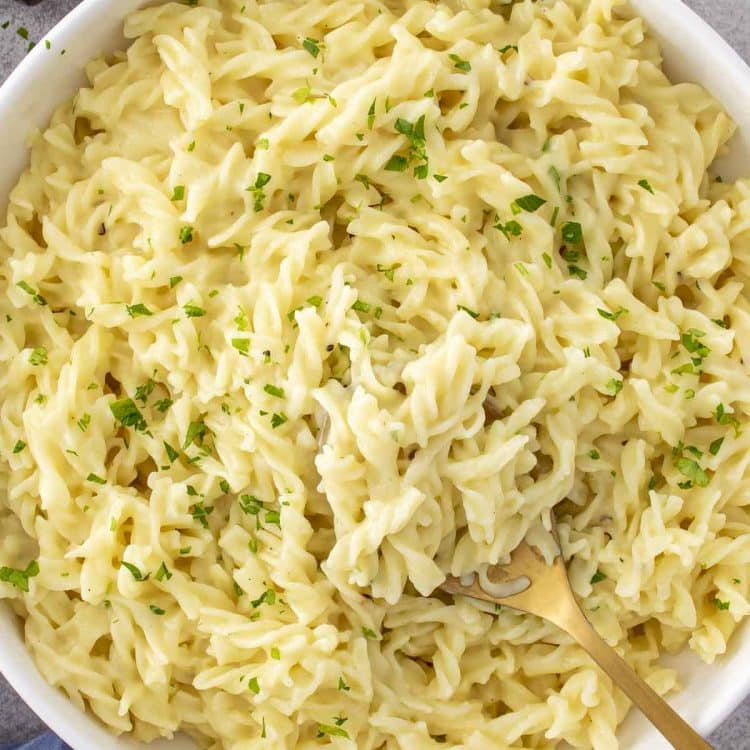 A big bowl of buttery cafeteria noodles made with egg noodles and cream of chicken, topped with fresh parsley.