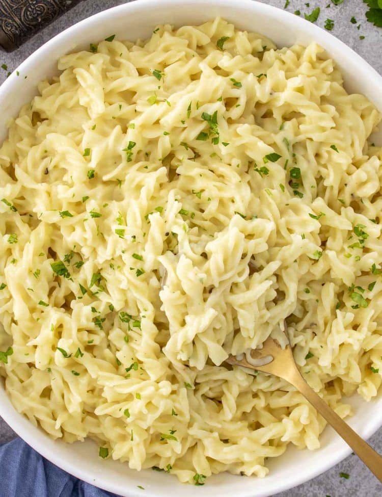 A big bowl of buttery cafeteria noodles made with egg noodles and cream of chicken, topped with fresh parsley.