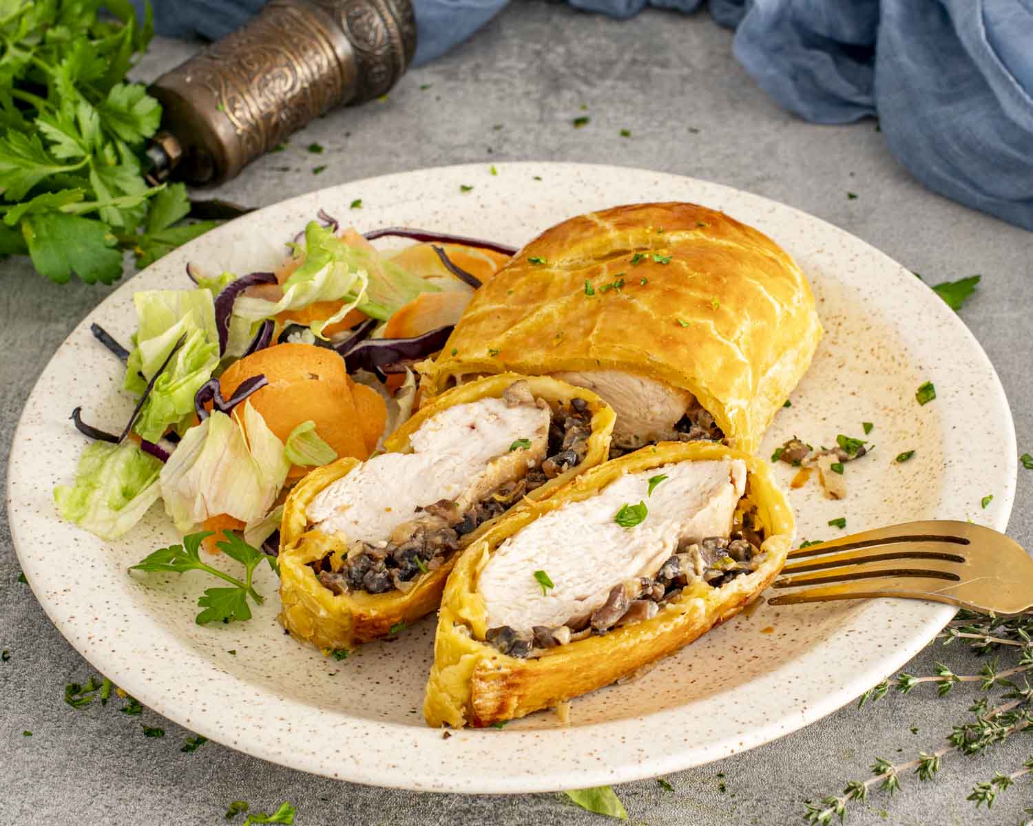 Sliced Chicken Wellington served with mixed salad, showcasing flaky puff pastry, tender chicken, and savory mushroom duxelles filling.