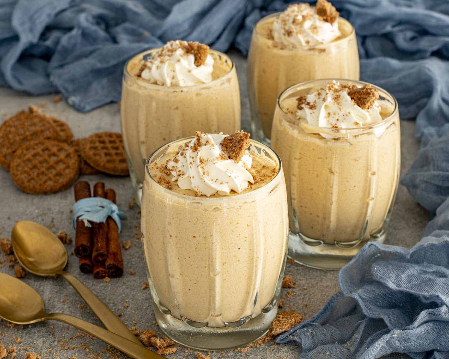 Creamy pumpkin mousse served in multiple glasses topped with whipped cream and gingersnap crumbs, an easy holiday no bake dessert.