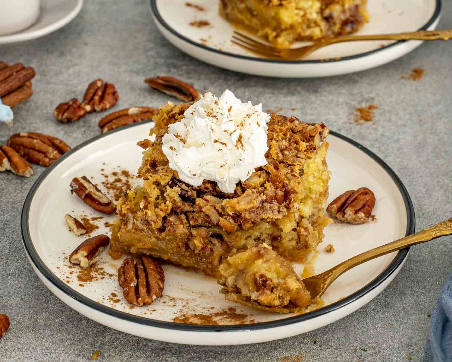 Slice of pumpkin pecan gooey cake with whipped cream and a forkful taken to show the rich gooey texture.