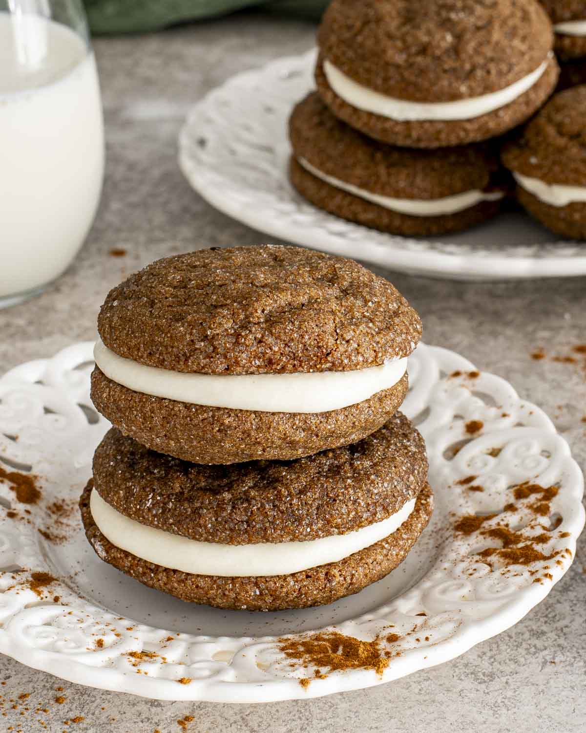 Stacked ginger molasses sandwich cookies with thick cream cheese filling, highlighting soft centers and warmly spiced cookie layers.