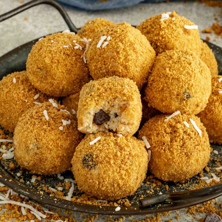 Moose Farts arranged on a dark tray, one with a bite revealing the chocolate chip center and soft coconut filling.