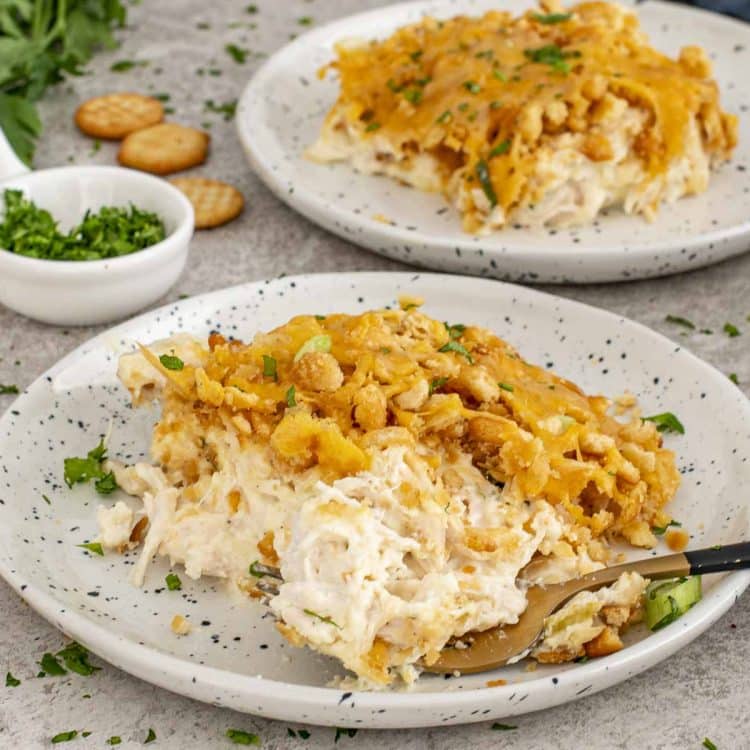 Two plates of Neiman Marcus Chicken Casserole with crispy buttery topping, creamy chicken interior, and parsley sprinkled for freshness.