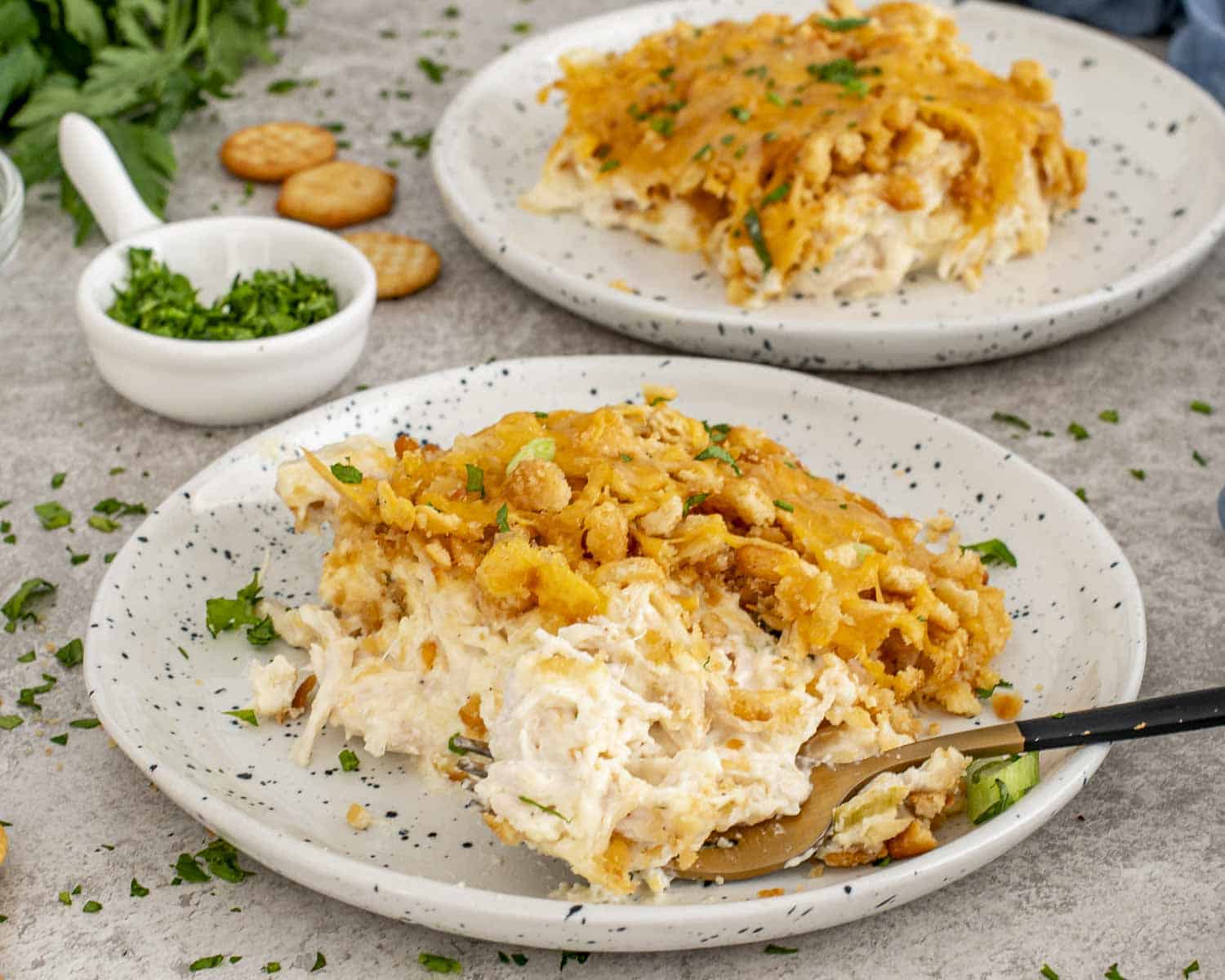 Two plates of Neiman Marcus Chicken Casserole with crispy buttery topping, creamy chicken interior, and parsley sprinkled for freshness.
