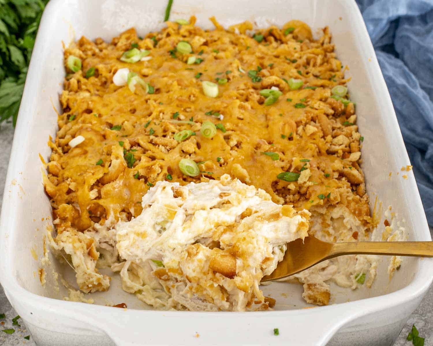 Creamy Neiman Marcus Chicken Casserole in a baking dish, showing crunchy cracker topping and soft chicken filling being served.