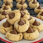 Soft peanut butter blossom cookies piled on a festive plate, showcasing crackly sugar coating and melty chocolate kiss centers.