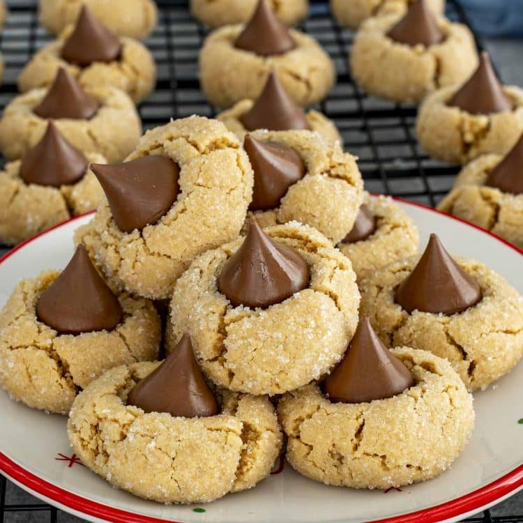 Soft peanut butter blossom cookies piled on a festive plate, showcasing crackly sugar coating and melty chocolate kiss centers.