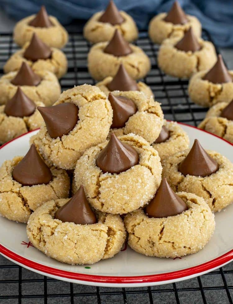 Soft peanut butter blossom cookies piled on a festive plate, showcasing crackly sugar coating and melty chocolate kiss centers.