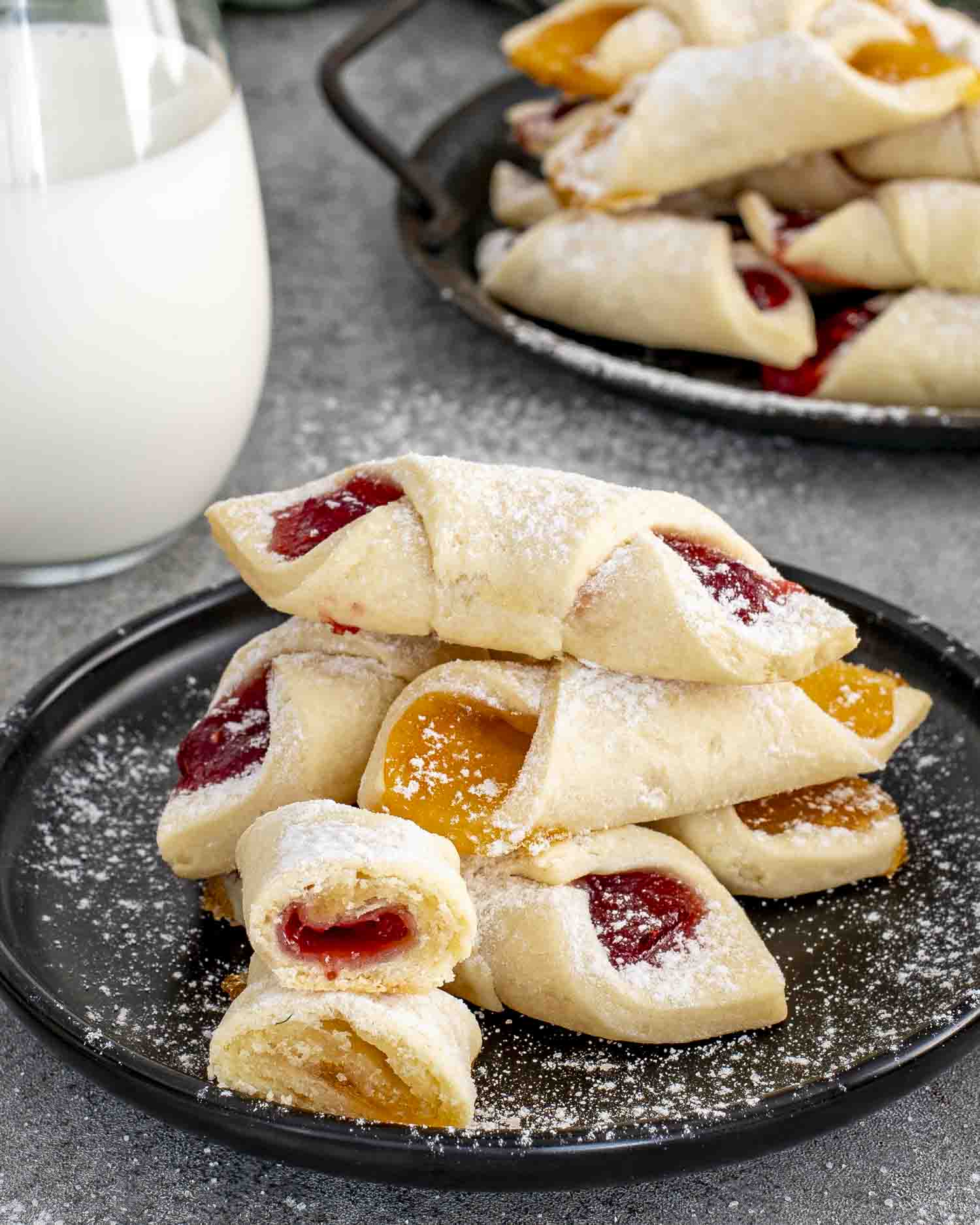Heaping tray of Polish Kolaczki cookies packed with apricot and raspberry preserves, dusted with powdered sugar for classic holiday style.