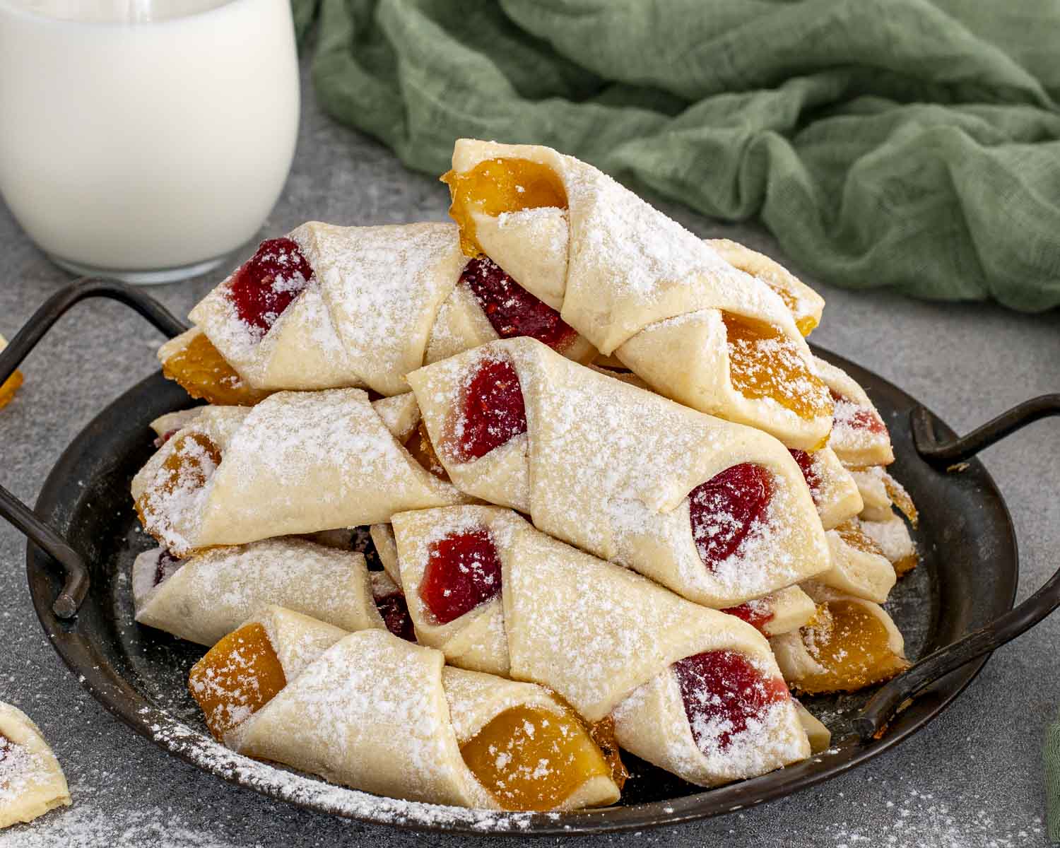 Large platter of assorted Polish Kolaczki cookies filled with vibrant fruit preserves and finished with a generous powdered sugar dusting.