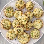 Overhead view of spinach dip stuffed mushrooms arranged on a serving platter, showing creamy filling and lightly browned cheese tops.