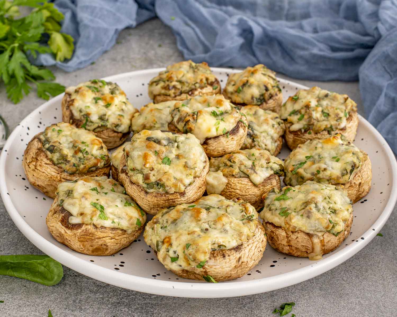 Large platter of spinach dip stuffed mushrooms garnished with parsley, ready to serve as an easy party appetizer.
