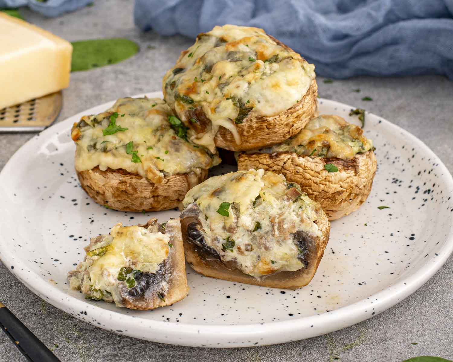 Side angle of spinach dip stuffed mushrooms on a plate, highlighting thick mushroom caps and rich, cheesy spinach filling.