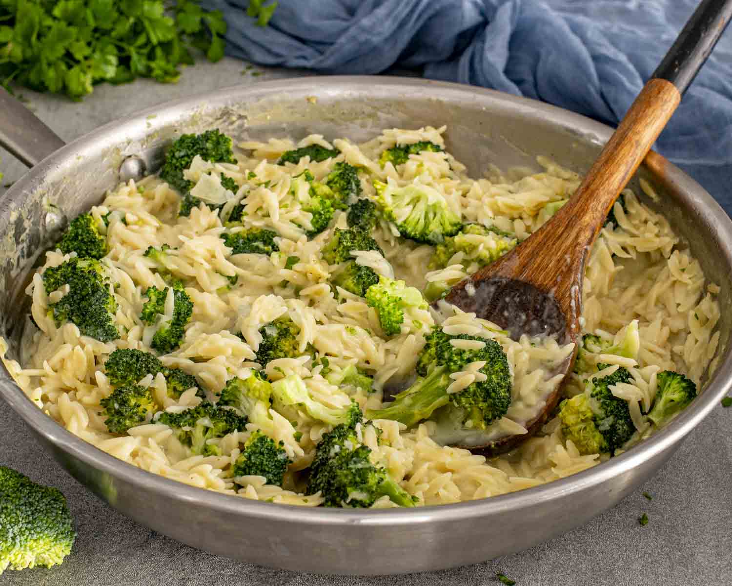One-pan broccoli cheddar orzo being stirred in a skillet, showing creamy texture, melted cheese, and evenly cooked broccoli.
