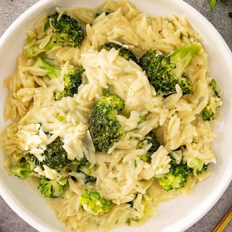Creamy broccoli cheddar orzo served in a white bowl, showing tender orzo coated in cheese sauce with broccoli.
