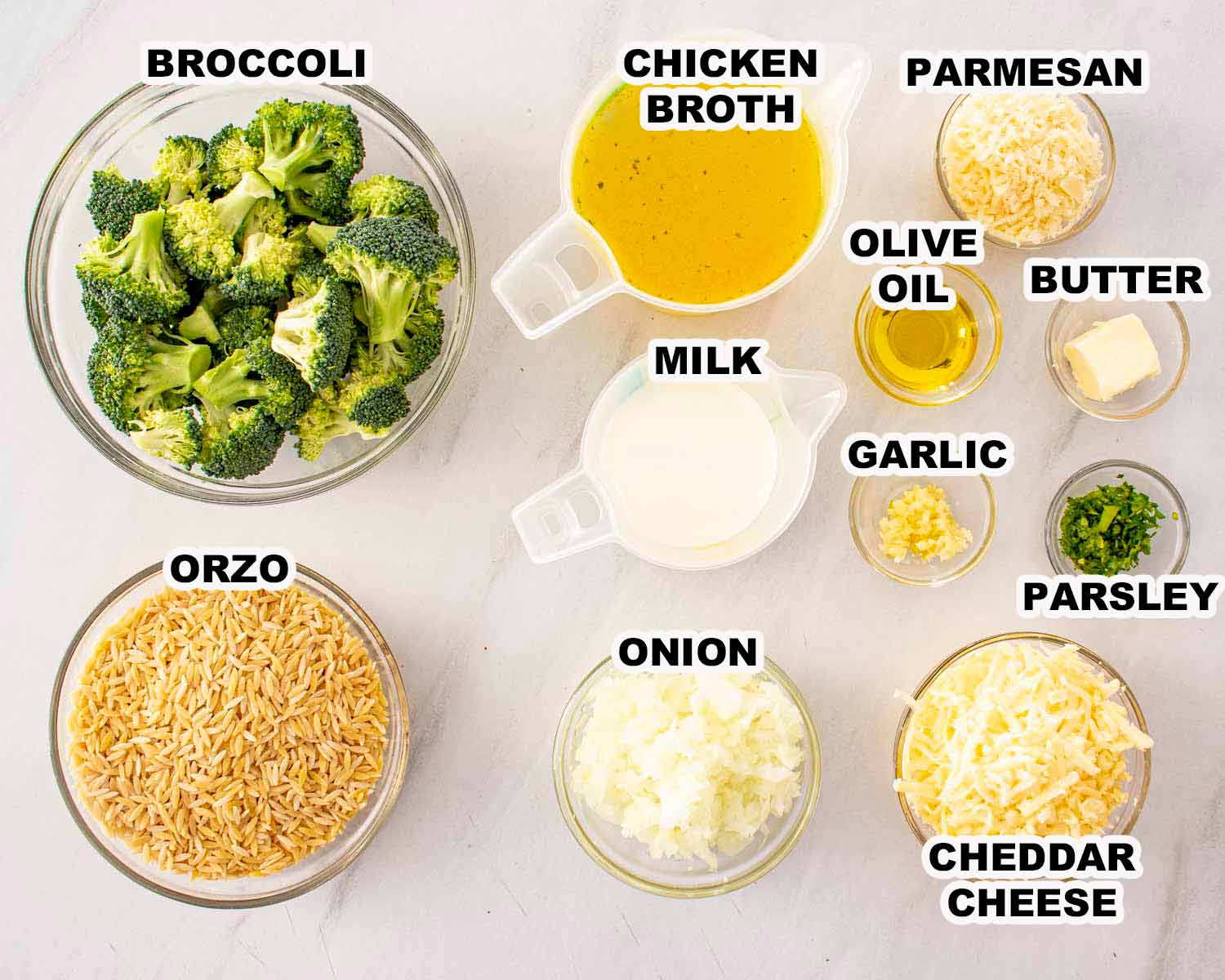 Ingredients for broccoli cheddar orzo including orzo pasta, broccoli florets, cheddar cheese, milk, butter, garlic, and broth.