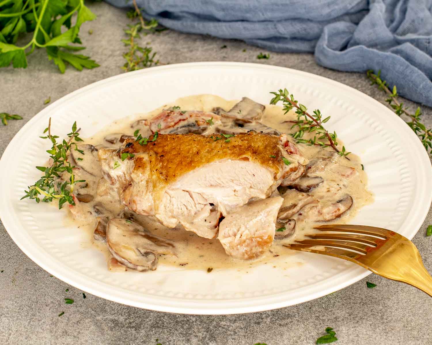 Close-up of coq au Riesling chicken thigh sliced open, showing juicy meat with creamy mushroom Riesling sauce.