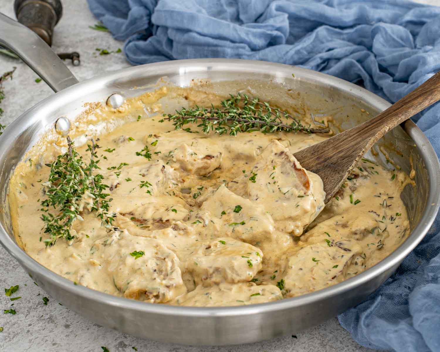 One-pan creamy garlic pork medallions cooking in a skillet with a thick Parmesan herb cream sauce.