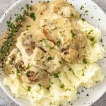 Creamy garlic pork medallions served over fluffy mashed potatoes, topped with fresh herbs and plenty of rich sauce.