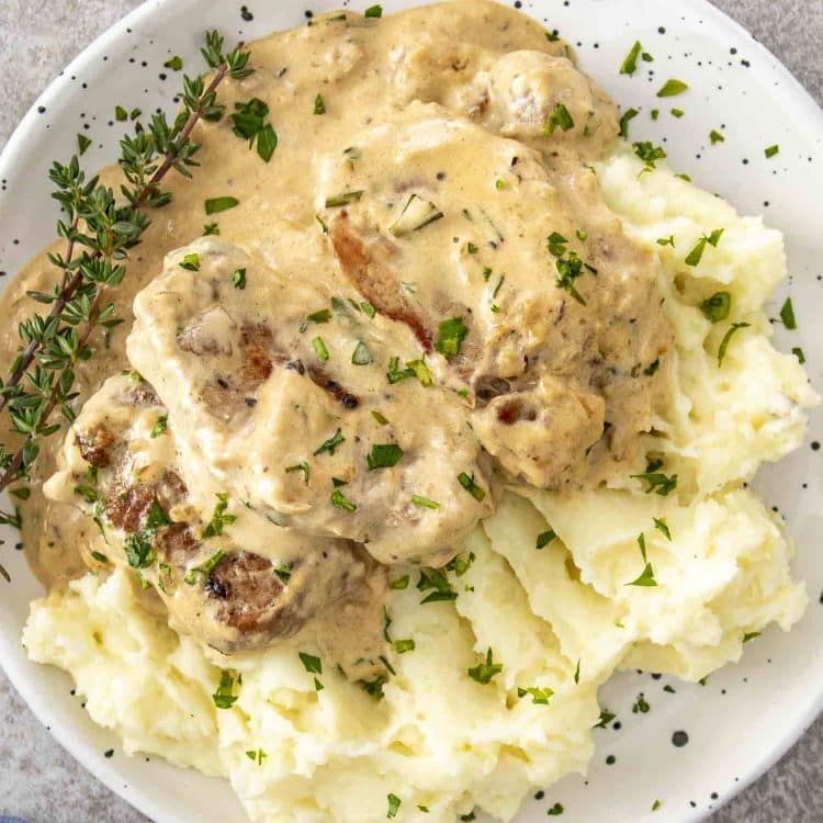 Creamy garlic pork medallions served over fluffy mashed potatoes, topped with fresh herbs and plenty of rich sauce.