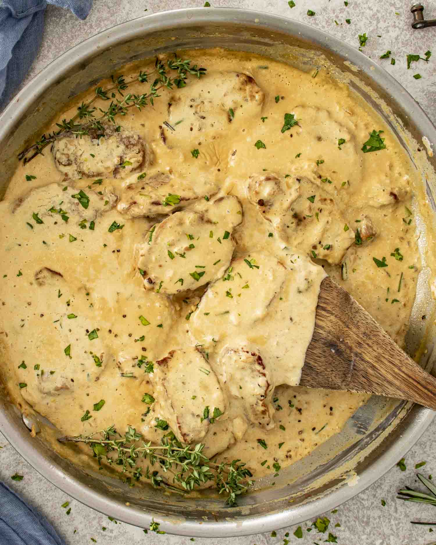 Creamy garlic pork medallions simmering in a skillet with a rich herb cream sauce, garnished with fresh thyme and parsley.