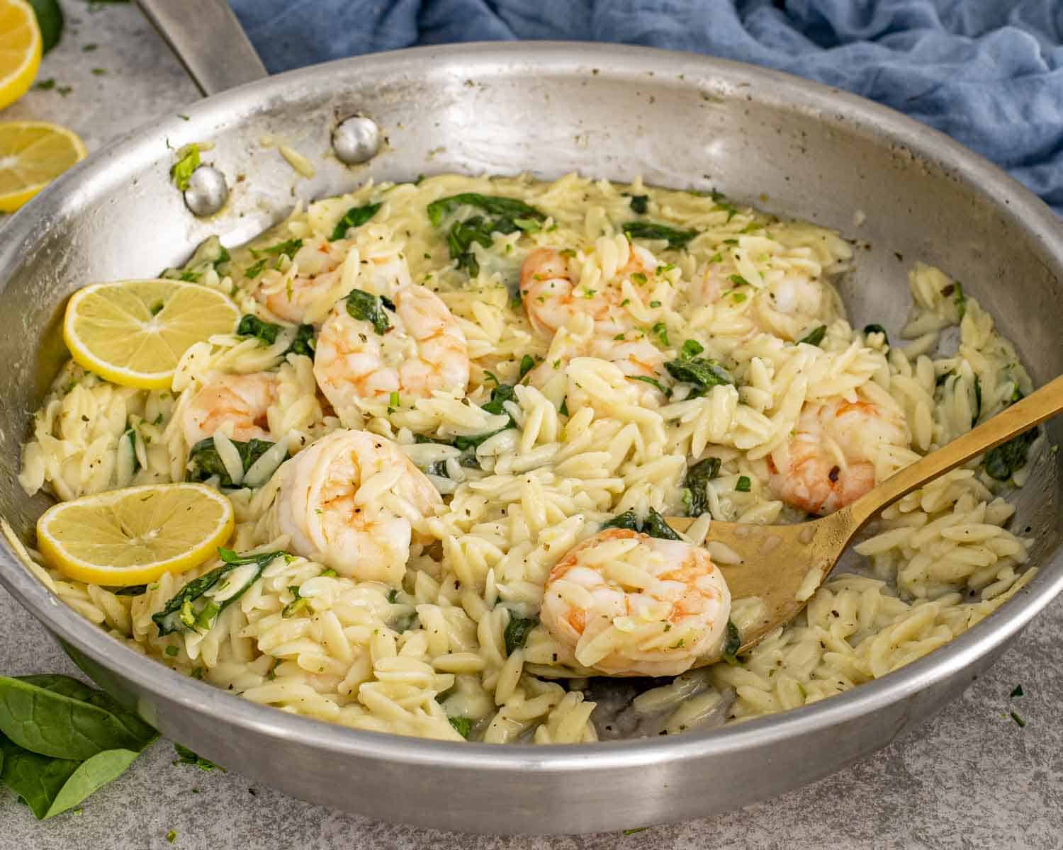 One-pan lemon garlic shrimp orzo cooking in a skillet with spinach, Parmesan, and lemon for an easy weeknight dinner.