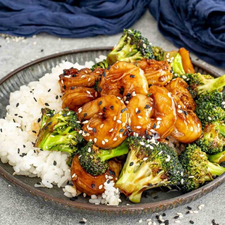 Shrimp and broccoli stir-fry served over steamed white rice, finished with sesame seeds and rich savory sauce.