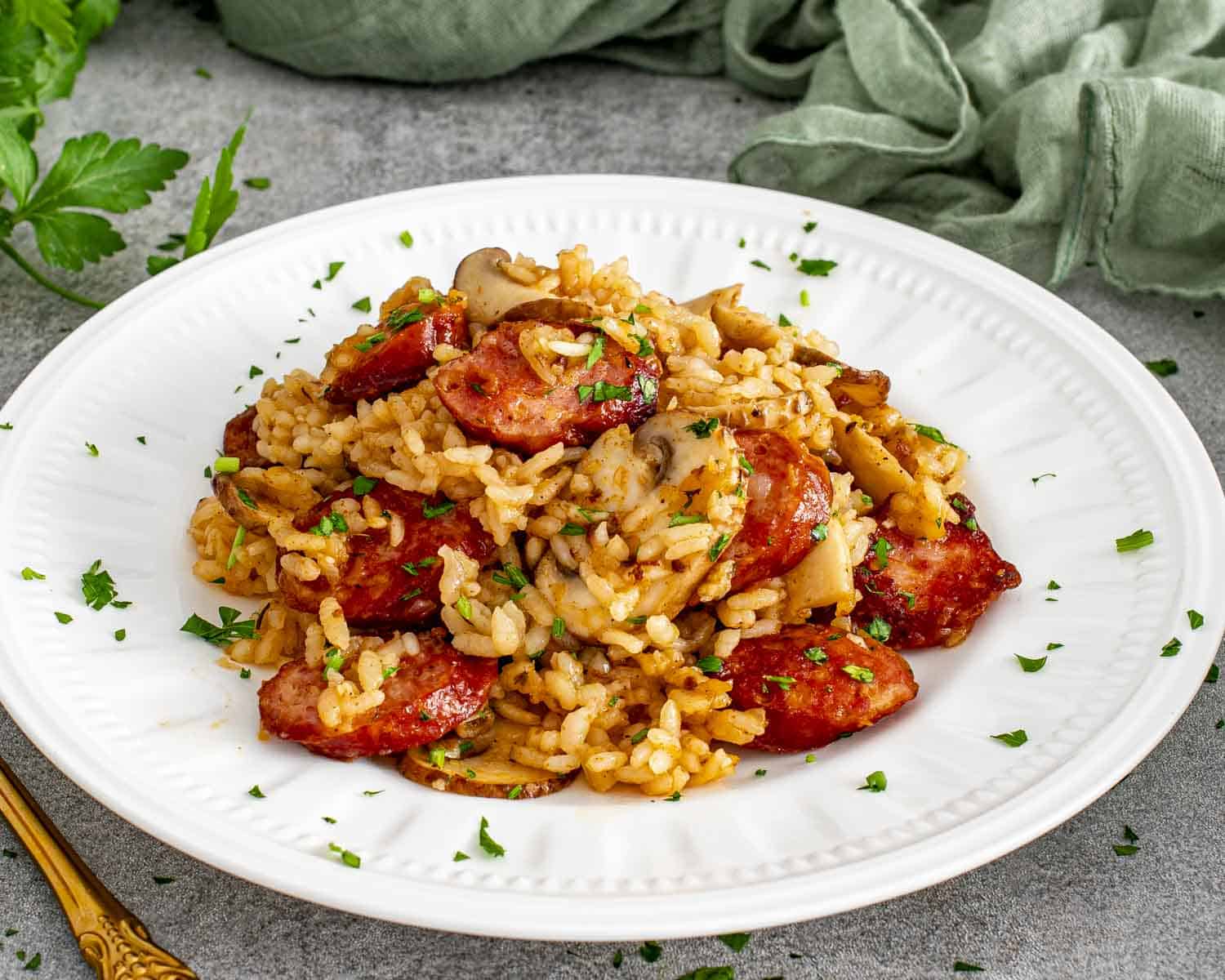 Close-up of sausage and mushroom rice plated for serving, highlighting smoky sausage rounds, sautéed mushrooms, and well-seasoned rice.