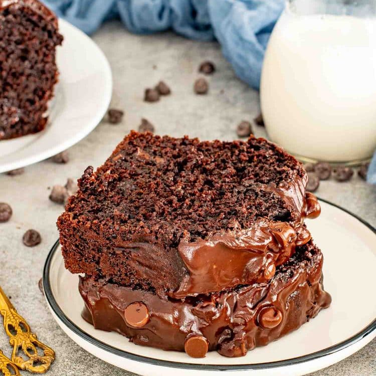 Chocolate loaf cake slice stacked on plate with thick chocolate ganache and scattered chocolate chips.