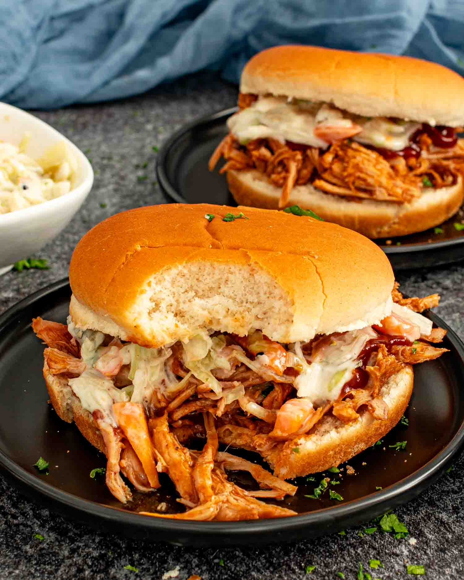 BBQ pulled pork slider with coleslaw and barbecue sauce, showing juicy shredded pork inside a soft bun.