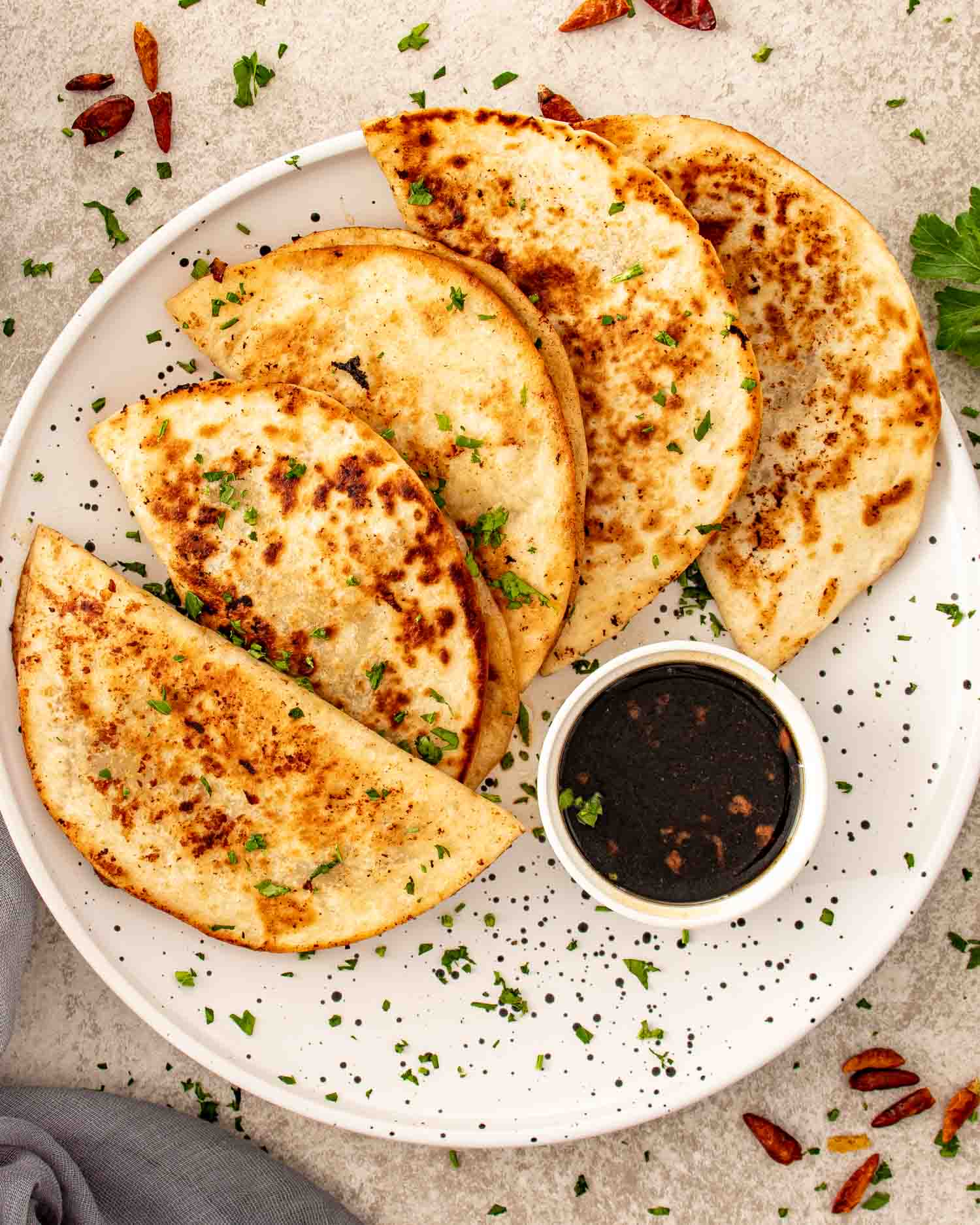 Golden crispy smashed dumpling tacos folded and served on a plate with a small bowl of soy dipping sauce.