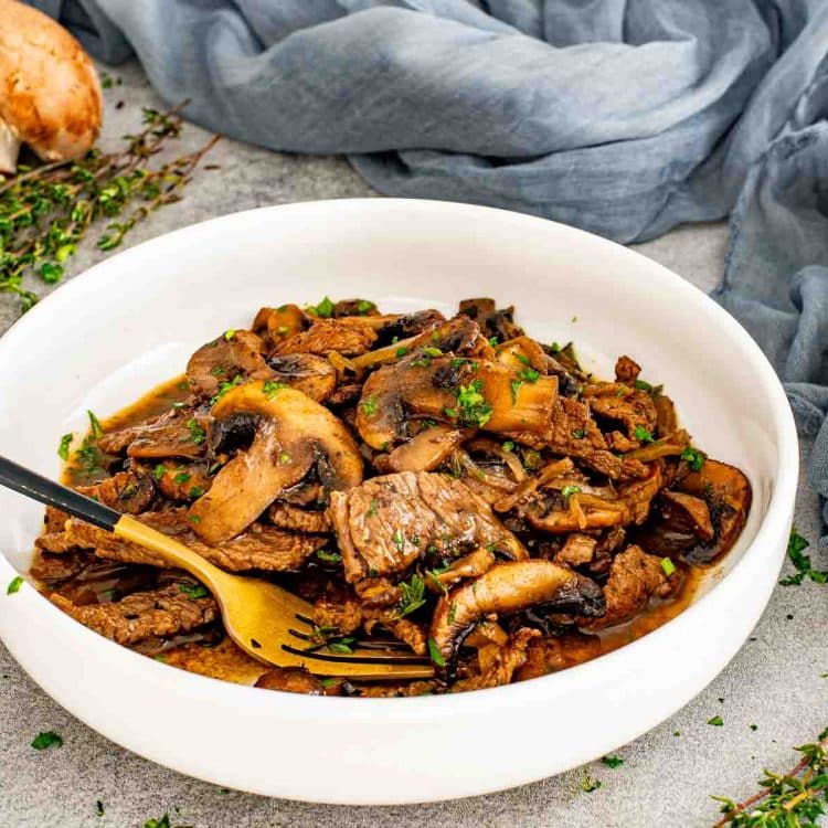Steak and mushroom skillet served in a white bowl with tender beef, sautéed mushrooms, onions, and rich pan sauce.