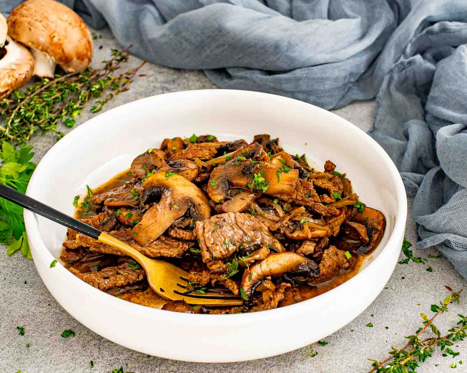 Steak and mushroom skillet served in a white bowl with tender beef, sautéed mushrooms, onions, and rich pan sauce.